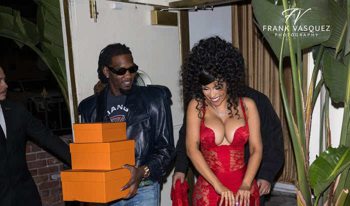 Model on a gold velvt couch wearing Frederick's of Hollywood's Rosalind collection corset and garter belt, both in black lace. 