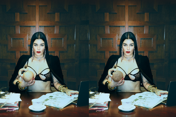 Model on a gold velvt couch wearing Frederick's of Hollywood's Rosalind collection corset and garter belt, both in black lace. 