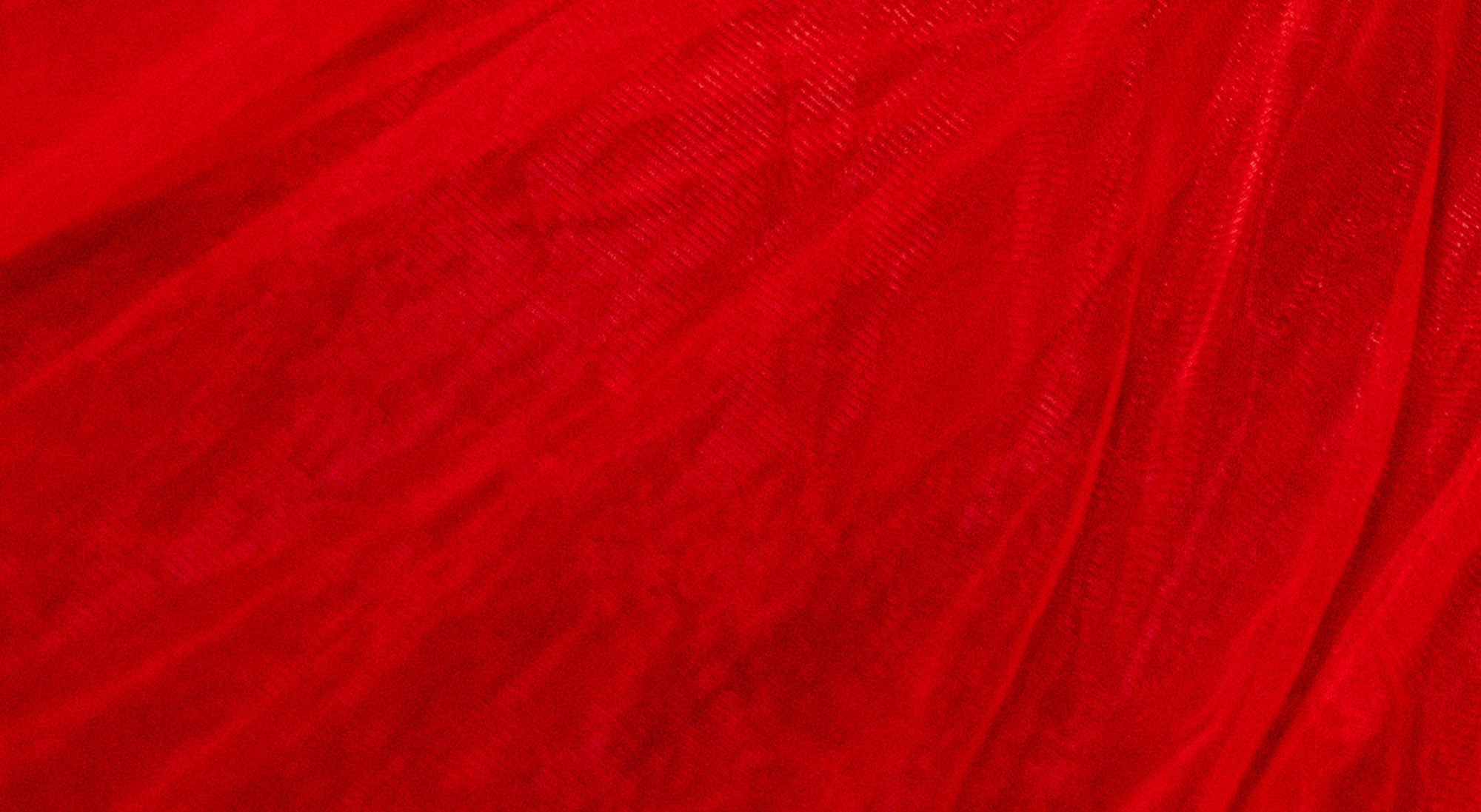 A close-up of bright red sheer mesh or tulle fabric with a textured nettle-like weave and soft folds.