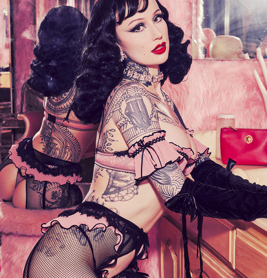 Woman wearing pink and black 2 piece lingerie with a reflection of her back in the mirror