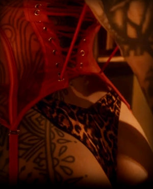 woman pulling red corset on a woman wearing leopard print thong underwear