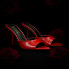 Red high-heeled shoes with open toes on a dark background with roses.