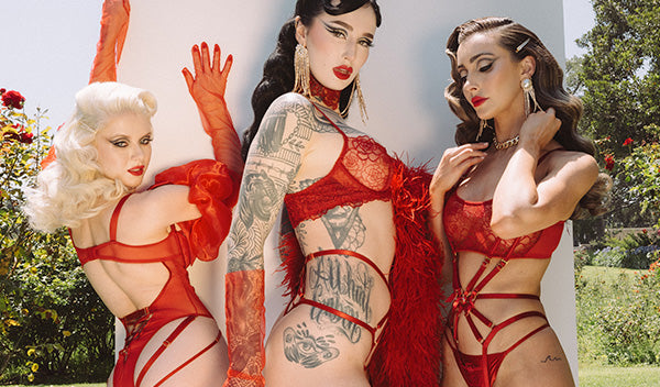 Three women in red lingerie with tattoos outdoors