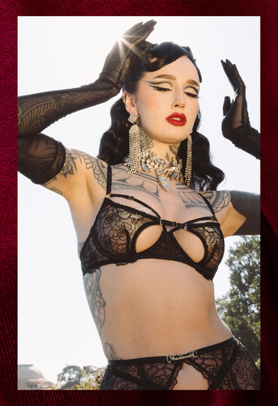 Person wearing black lace lingerie outdoors with a blurred background