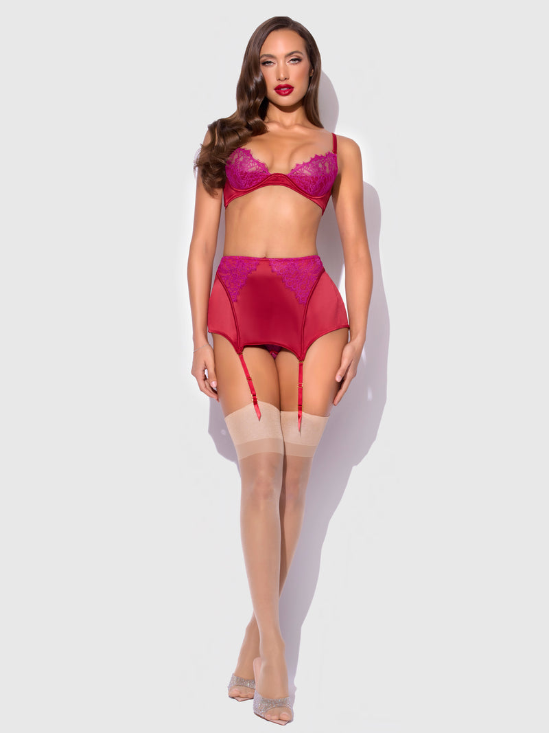 A woman poses against a plain light background wearing the Frederick's of Hollywood Rosalind Lace & Satin Open Back Garter Skirt, featuring red lace details and a high-waisted design paired with sheer stockings.