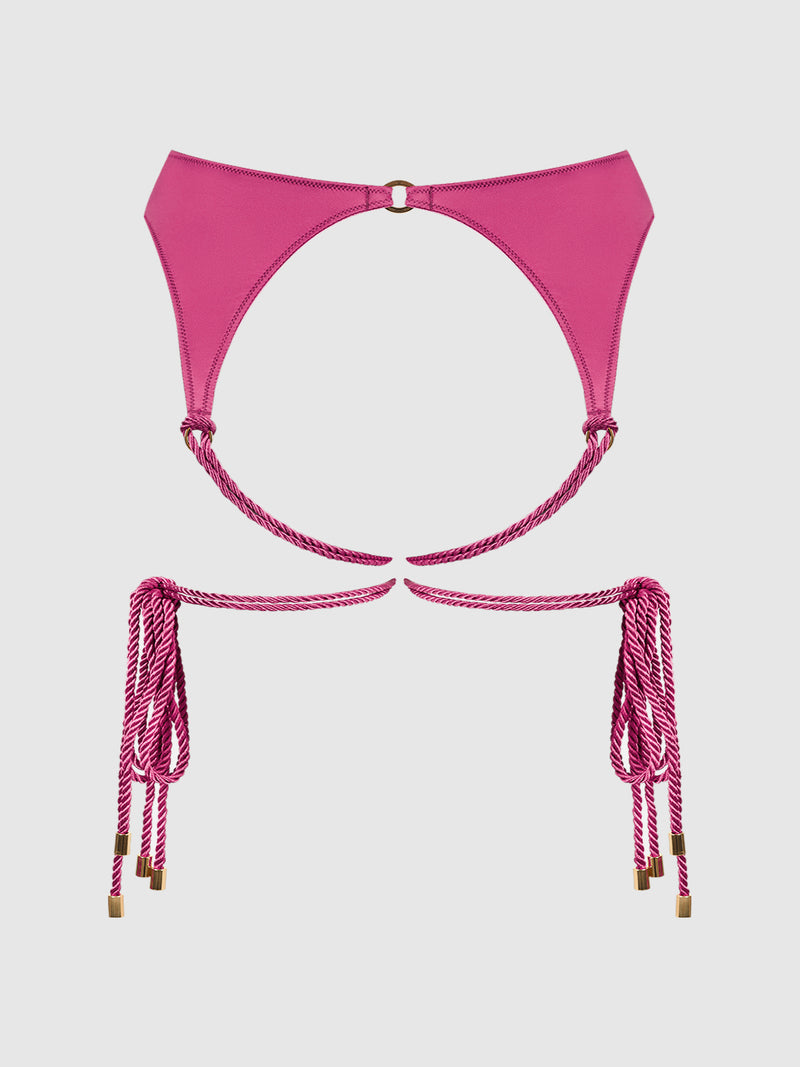 Introducing the Nadya Liquid Satin & Rope Garter by Frederick’s of Hollywood—a minimal and stylish garter in vivid pink satin, featuring luxurious rope-like straps with gold tips. Gold accents elevate the design, giving it a striking look that stands out against a plain white background.
