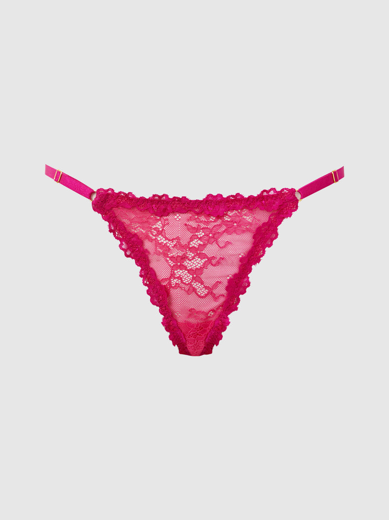 The Pia Lace Side Slider Thong by Frederick's of Hollywood features hot pink stretch lace, floral patterns, minimal coverage, ruffled edges, and adjustable side straps, shown on a plain light background.