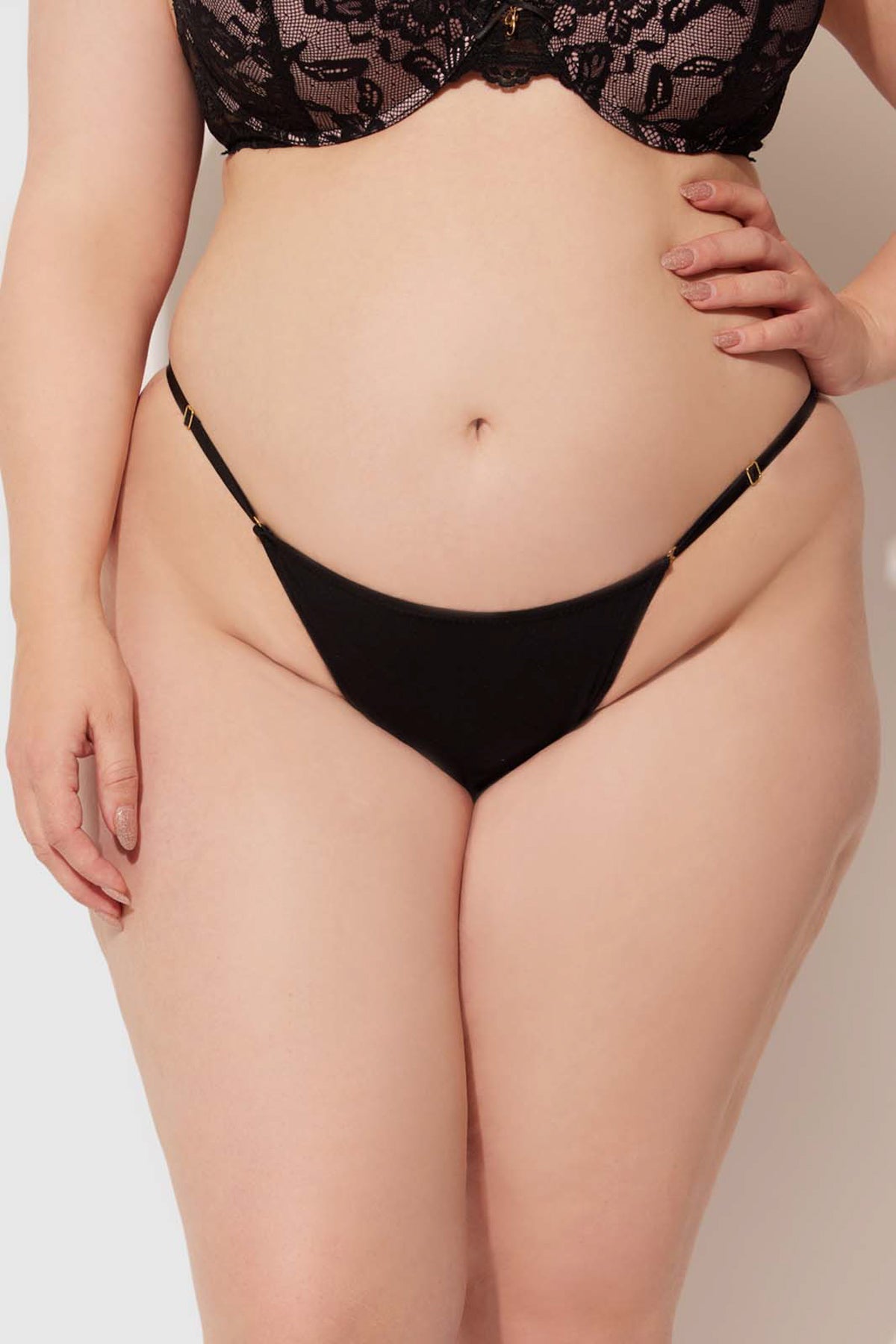 A plus-size model in the Bailey Stretch Cotton Bikini by Frederick's of Hollywood poses confidently against a plain light background, with one hand on their hip.