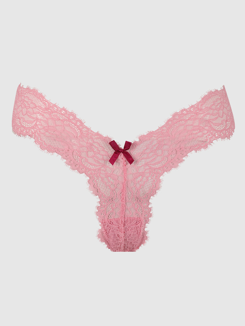 The Lulu Lace V-Thong by Frederick's of Hollywood features pink lace with scalloped edges, minimal back coverage, and a dark pink bow at the center front, shown against a plain light gray background.