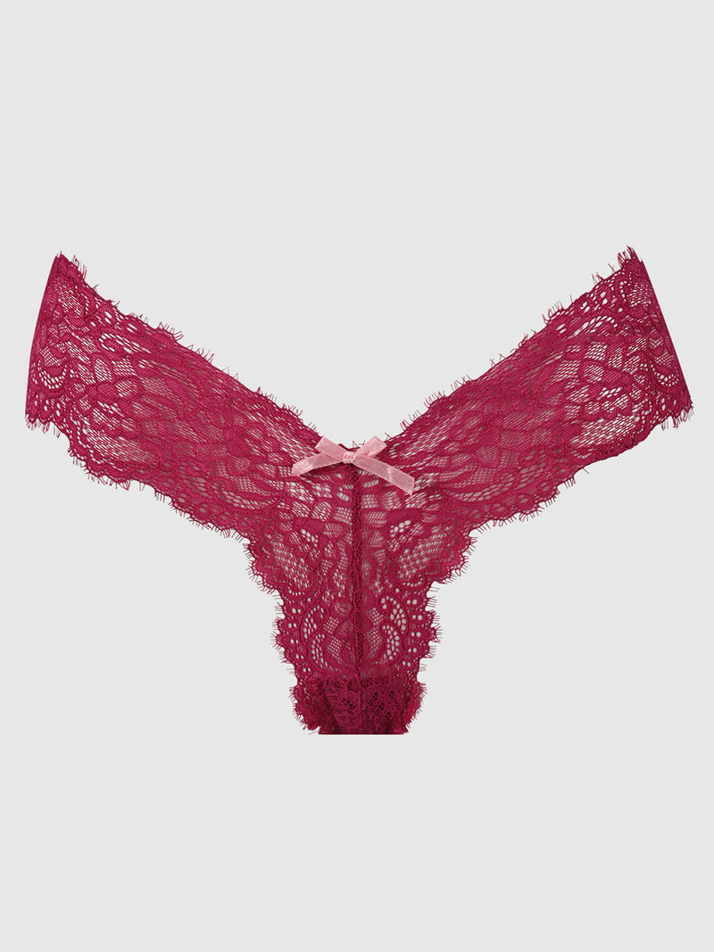The Lulu Lace V-Thong by Frederick's of Hollywood features burgundy stretch lace with scalloped edges and a pink ribbon bow at the front, offering minimal back coverage. Displayed on a light gray background.