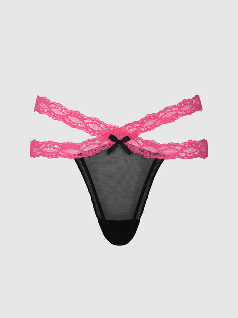 The Stella Mesh & Lace Double Band Thong by Frederick’s of Hollywood features black mesh fabric with two pink lace straps crossing at the sides and a small black bow at the front center, displayed against a plain light gray background.