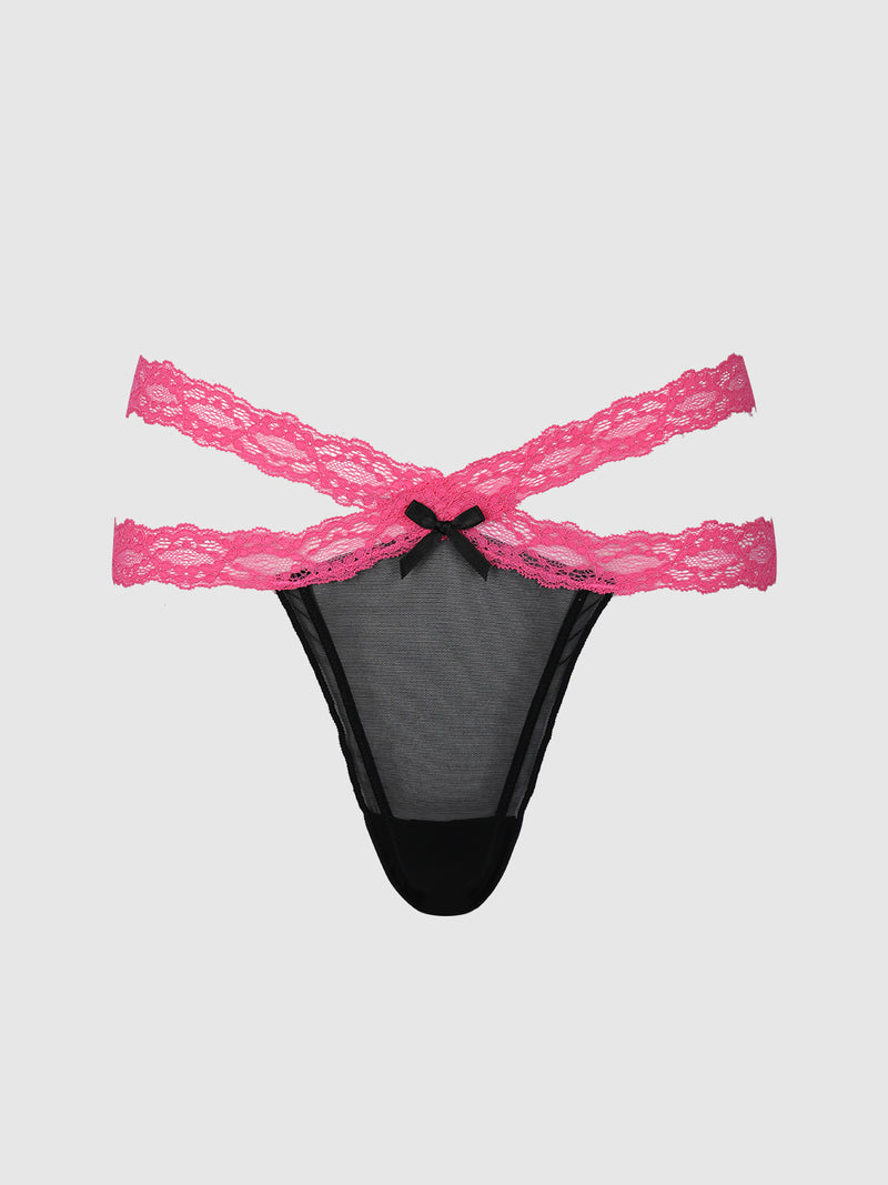 The Stella Mesh & Lace Double Band Thong by Frederick’s of Hollywood features black mesh fabric with two pink lace straps crossing at the sides and a small black bow at the front center, displayed against a plain light gray background.