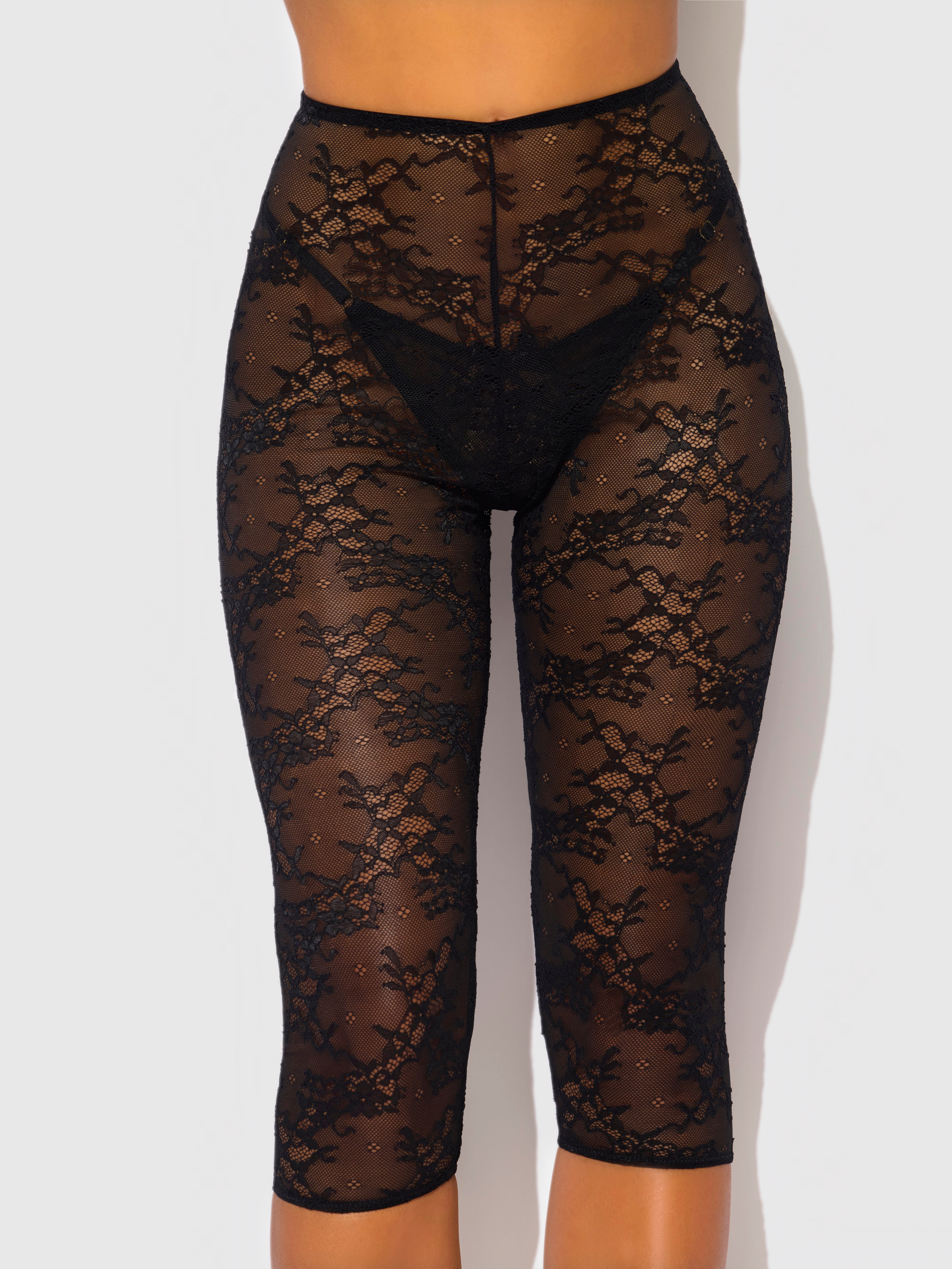 Someone wears Frederick's of Hollywood Pia Lace Capri Legging Tights, which are high-waisted, black, semi-transparent with a floral lace pattern, and reach below the knees. The background is plain and light-colored.