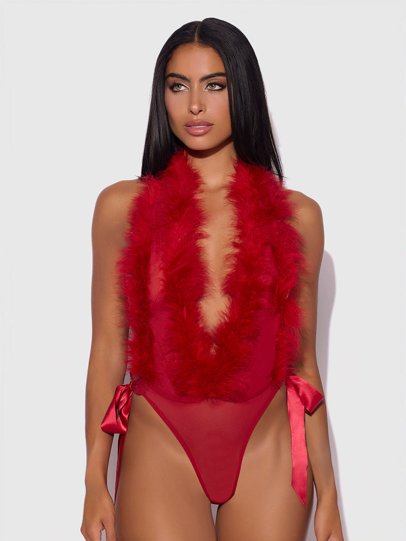 A woman with long, straight black hair models the Frederick's of Hollywood Scarlett Plunging Drop Off Marabou Teddy in red, featuring feather trim, a deep neckline, and satin side bows against a plain light background.
