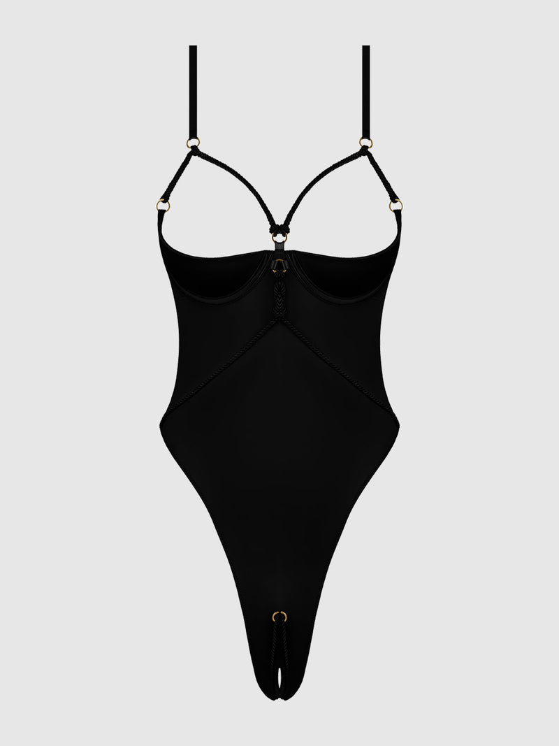 The Nadya Liquid Satin & Rope Crotchless Teddy by Frederick's of Hollywood is a black strappy bodysuit with thin adjustable straps, gold ring accents, underwire cups, and high-cut legs, shown on a plain light gray background.