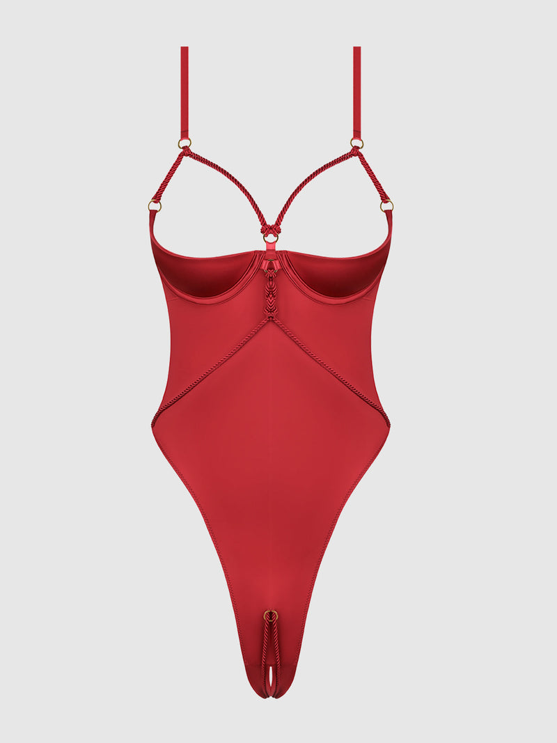 The Nadya Liquid Satin & Rope Crotchless Teddy by Frederick's of Hollywood is a red, strappy satin bodysuit with open cups, high-cut legs, gold rings, rope accents, a keyhole front, smooth finish, and adjustable straps.