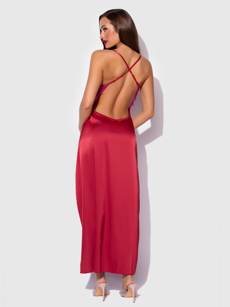 A woman with long brown hair and high heels poses against a light background wearing the Frederick's of Hollywood Rosalind Satin & Lace Long High Slit Gown, featuring shiny fabric, lace details, a low-cut back, and crisscross straps.