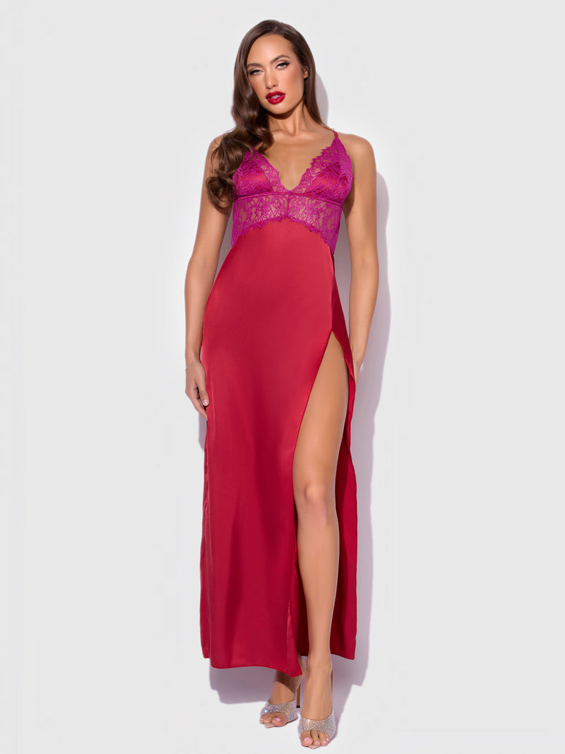 A woman in the Rosalind Satin & Lace Long High Slit Gown by Frederick's of Hollywood stands against a plain light background, her long brown hair and silver heels completing the elegant sleepwear look.