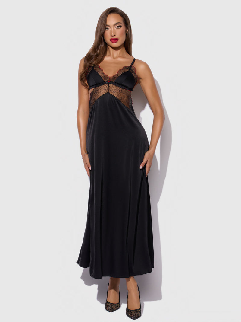A woman with long brown hair and red lipstick wears the Frederick's of Hollywood Ilaria Embroidered Tulle Triangle Top Long Gown against a light gray background, paired with black shoes.