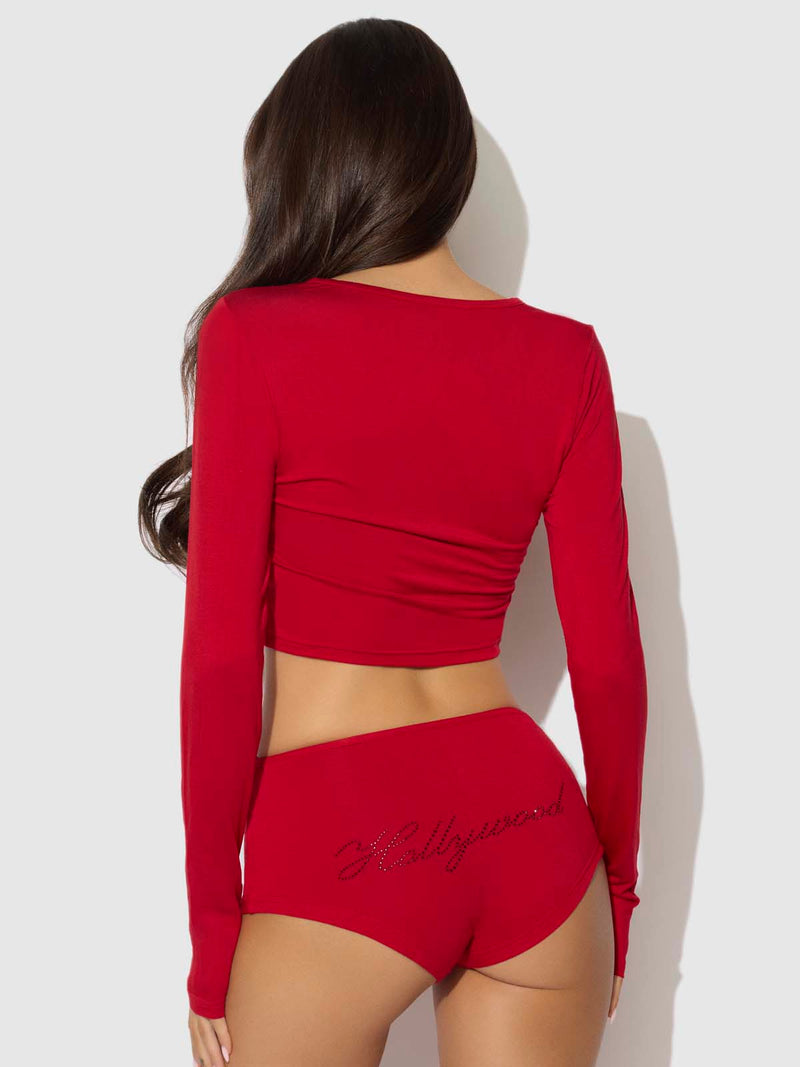 A person wearing a Seraphina Modal Long Sleeve Crop And Short Sleep Set in red, featuring a long-sleeve cropped top and matching shorts with Hollywood spelled out in rhinestones on the back.