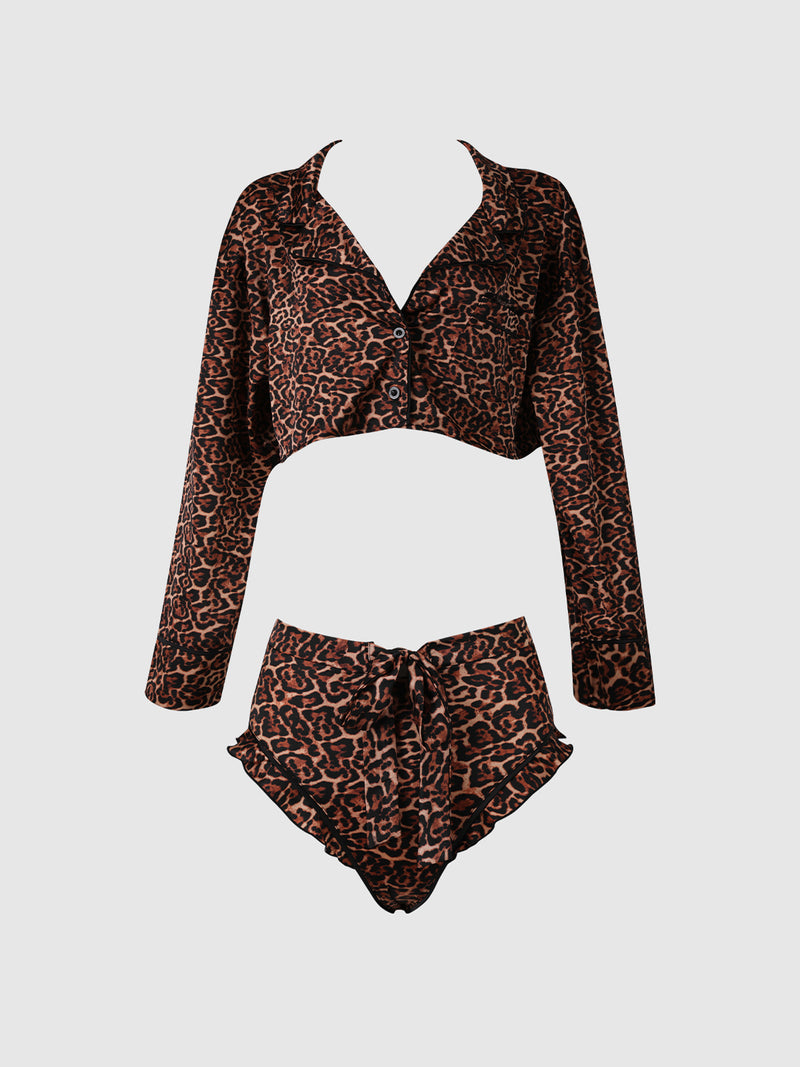 The Raven Leopard and Lace Sleep Set by Frederick's of Hollywood features a chic two-piece design with a brown and black leopard print. The set includes a long-sleeve, cropped button-up shirt and matching high-waisted shorts, complete with a drawstring waist and ruffled edges.