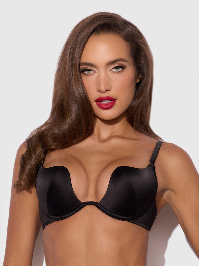 A woman wearing a black satin Frederick’s of Hollywood Petra Rising Star Plunge Push Up Bra.