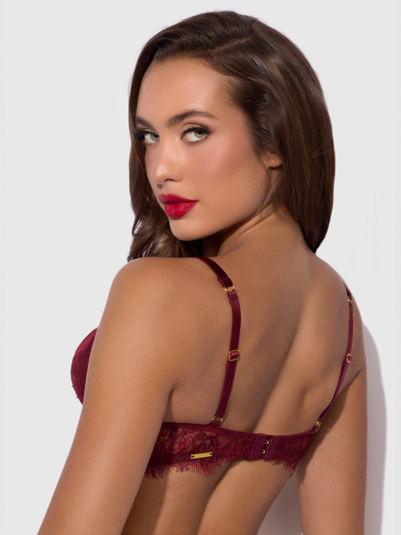 A woman wearing a dark red Lilith Lace & Mesh V Wire Bra with thin straps, shown from the back while looking over her shoulder.