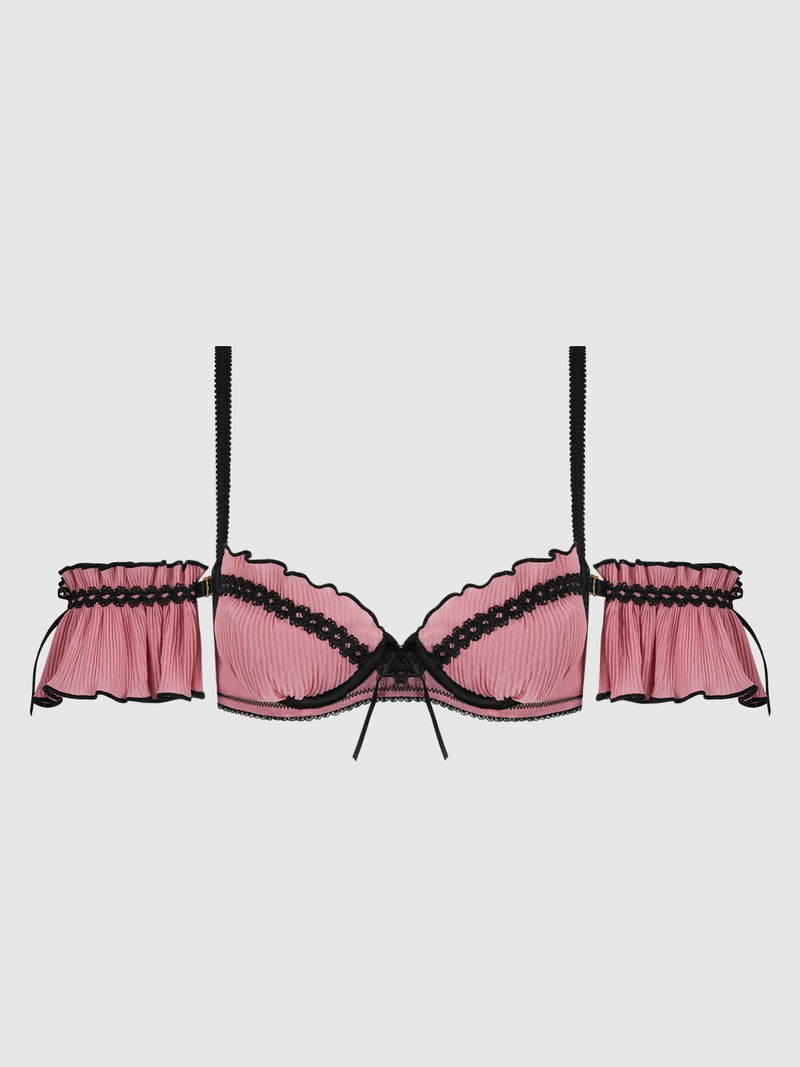 The Esme Pleated Chiffon & Lace Drop Shoulder Bra by Frederick’s of Hollywood features pink pleated chiffon, black lace trim, black straps, and decorative side ruffles, shown against a plain white background.