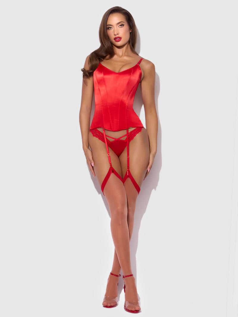 A woman wearing a red satin Frederick’s of Hollywood Iconic Full Boning Scoop Neck Corset with matching lace thong and attached garter straps.