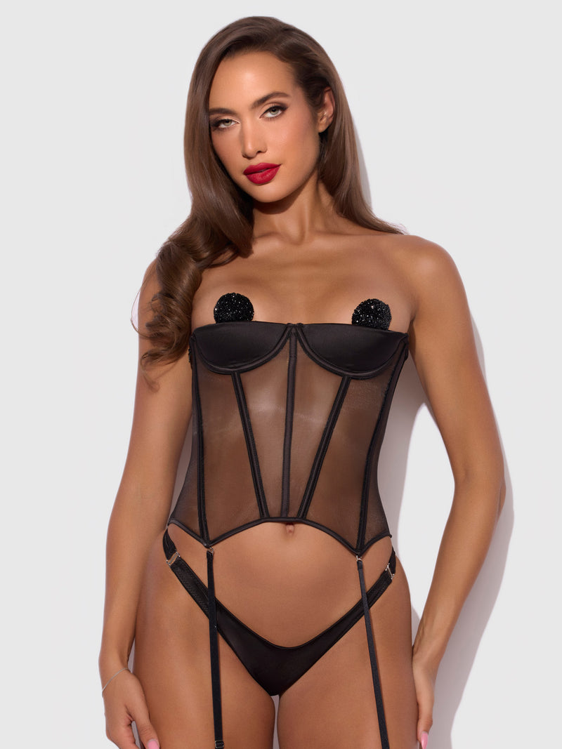 A model wearing a black Petra Satin Open Cup Satin Corset with glittery circular covers and matching gartered briefs.