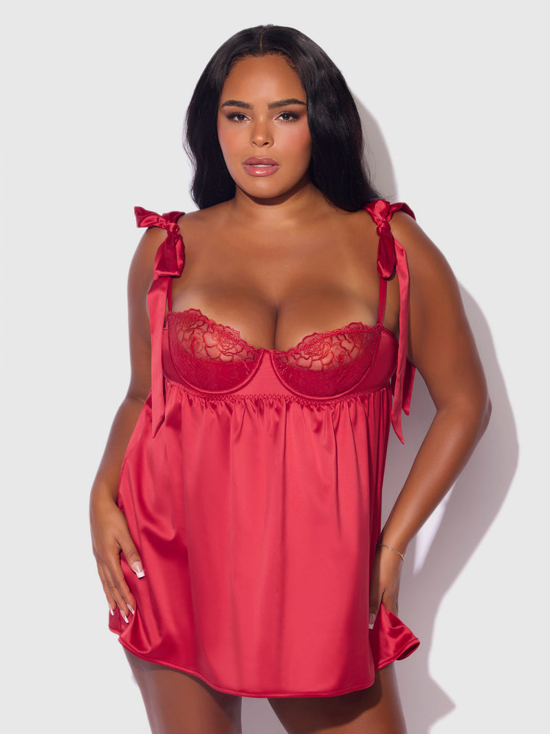 A woman models the Melrose Satin & Embroidered Lace Underwire Babydoll Set by Frederick's of Hollywood, featuring bow-detailed straps, against a plain light background.