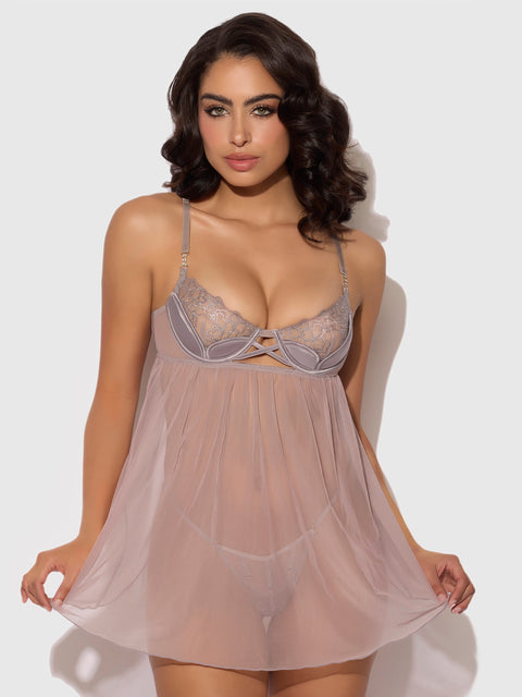 A woman with wavy dark hair models the Frederick's of Hollywood Wren Satin & Embroidered Tulip Demi Babydoll, holding out the sides of its flowy skirt while posing against a plain light background.