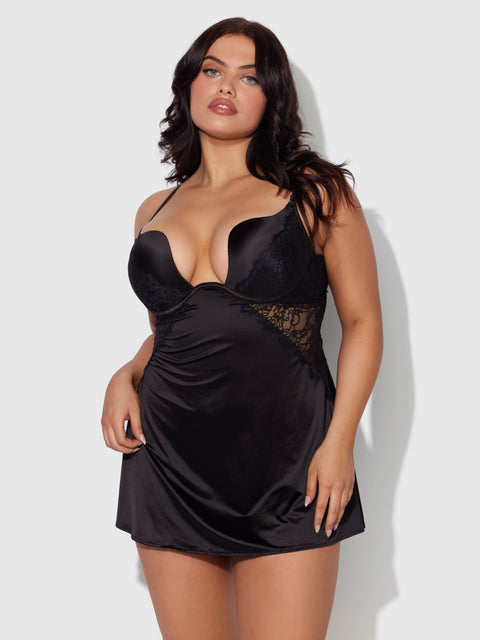 A woman with long dark hair models the Frederick's of Hollywood Rising Star Plunge Push Up Babydoll in liquid satin and lace, featuring a deep neckline, as she looks confidently at the camera against a light gray background.