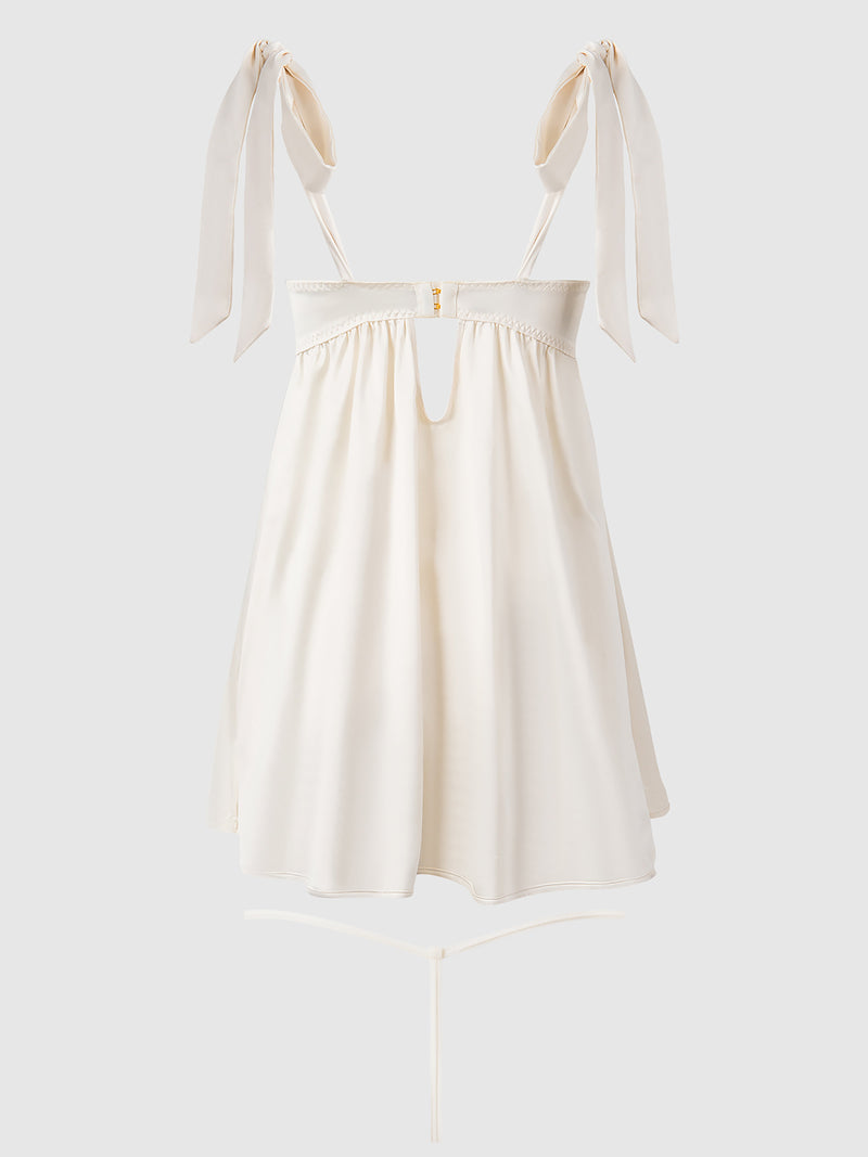 The Petra Satin Open Cup Babydoll by Frederick's of Hollywood is a sleeveless ivory mini dress featuring adjustable bow-tied straps, a fitted bodice with satin accents, front cut-out, and flowy A-line skirt for a delicate, lingerie-inspired look.