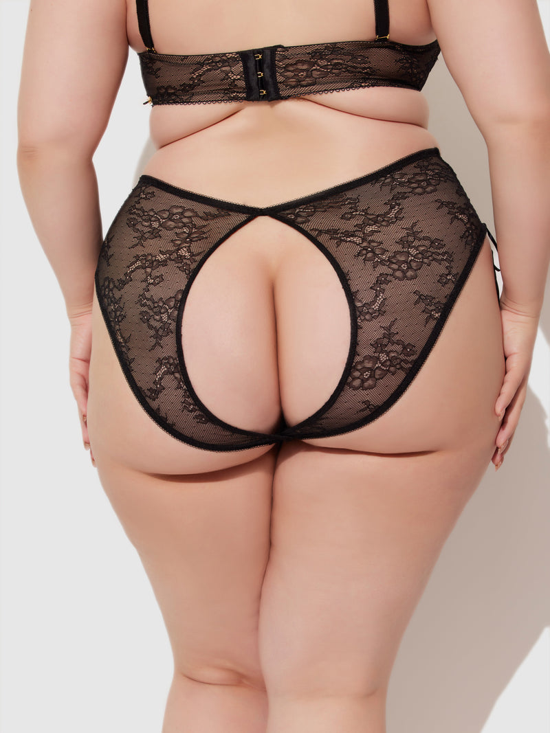 A person wearing the Frederick's of Hollywood Luella Lace Open Back High-Waist Panty is shown from the back, with cut-out details revealing part of the buttocks and highlighting the intricate black lace design.