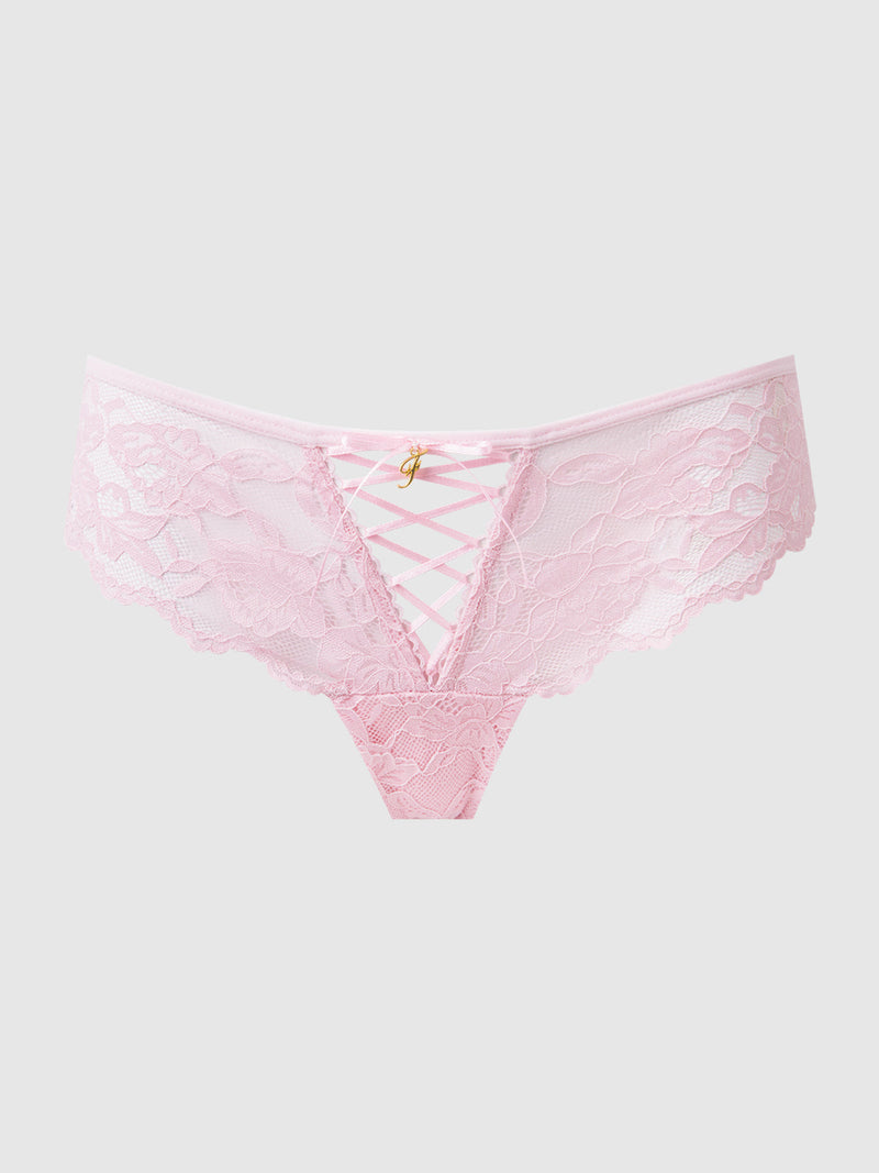 The Mabel Lace Up Front Tanga by Frederick's of Hollywood features light pink lace with a floral design, crisscross ribbon detail at the front, and a gold charm on the waistband, displayed against a simple pale backdrop.