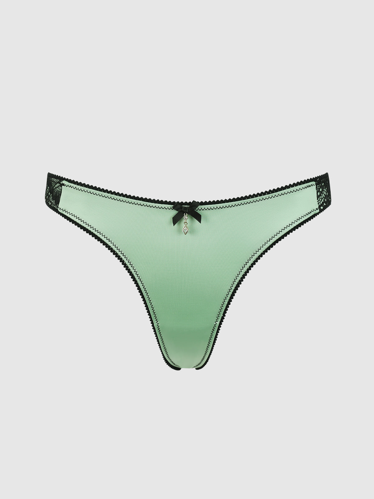 The Lexi Liquid Satin & Lace V-Tanga Panty by Frederick's of Hollywood features mint green satin, black lace trim, a small black bow, and a decorative front charm, shown against a plain white background.