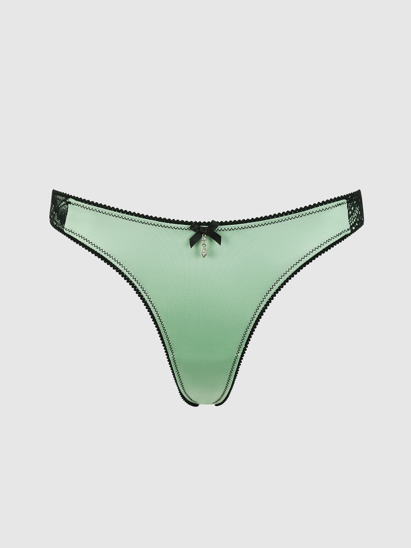 The Lexi Liquid Satin & Lace V-Tanga Panty by Frederick's of Hollywood features mint green satin, black lace trim, a small black bow, and a decorative front charm, shown against a plain white background.
