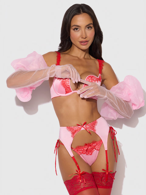 Model wearing Frederick's of Hollywood Chiffon Long Glove With Puff, styled with pink and red lace lingerie, matching red stockings, and sheer puff sleeves against a plain white background.