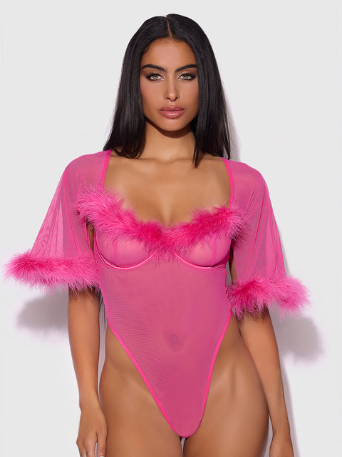 A woman with long dark hair models the Frederick's of Hollywood Scarlett Bell Sleeved Marabou Bodysuit, a sheer hot pink piece with feather trim on the neckline and bell sleeves, standing against a plain white background.