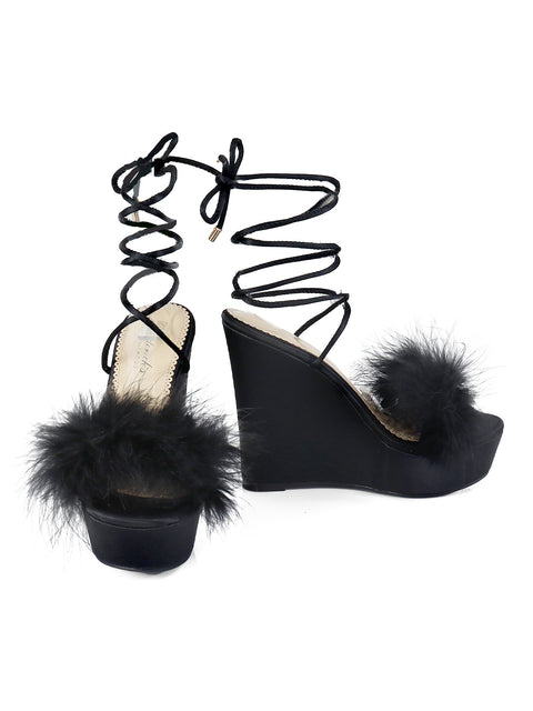 The Adriana Feather Wedge by Frederick's of Hollywood features black strappy high heels with fluffy feather toe details and lace-up ankle ties—perfect for adding drama to your black lingerie look.