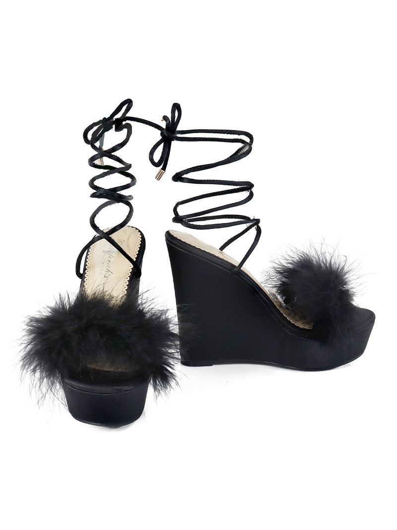 The Adriana Feather Wedge by Frederick's of Hollywood features black strappy high heels with fluffy feather toe details and lace-up ankle ties—perfect for adding drama to your black lingerie look.