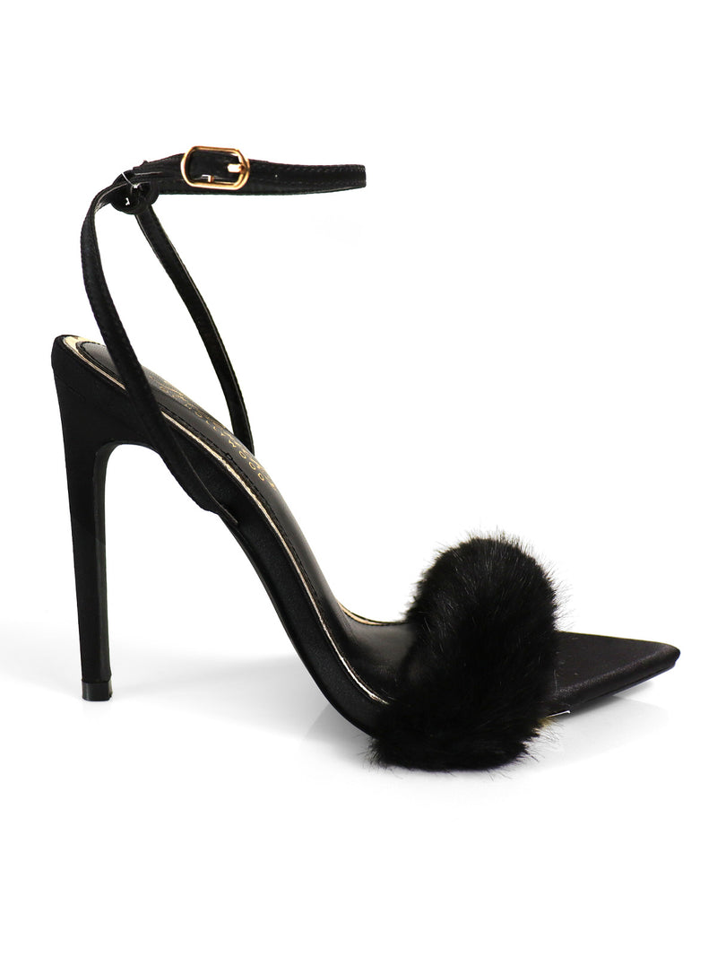 The Aileen Pointed Toe Heel by Frederick's of Hollywood is a black heel with a timeless design, an ankle strap with gold buckle, and a fluffy black fur band—perfect for lovers of elegant footwear.