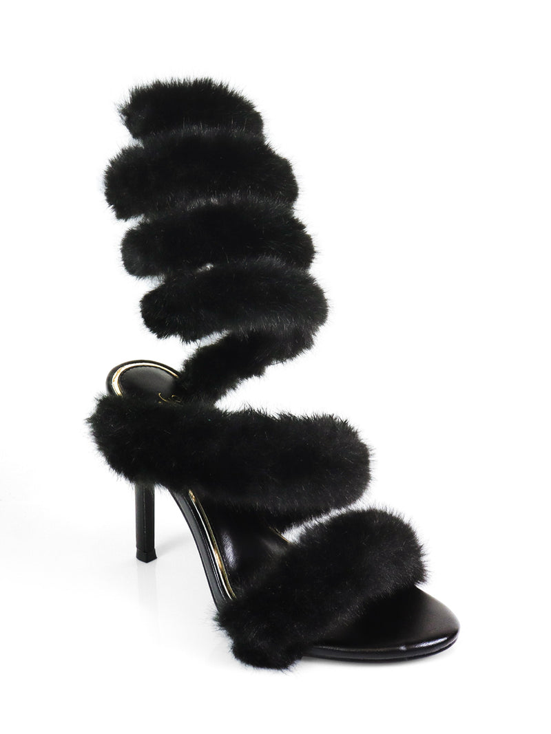 The Allure Fluffy Stiletto Sandal by Frederick's of Hollywood features three thick black faux fur straps spiraling from toe to above the ankle, creating glamorous statement heels displayed on a white background.