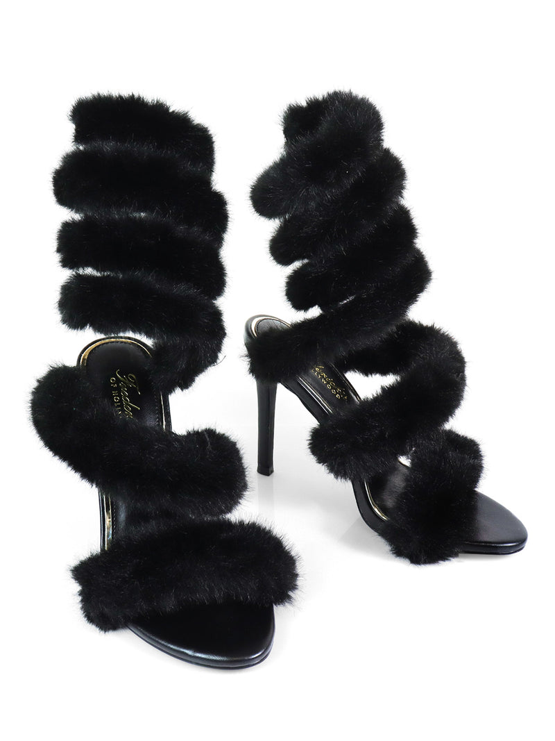 The Allure Fluffy Stiletto Sandal by Frederick's of Hollywood is a pair of black heels with multiple thick faux fur straps spiraling from toes to ankles, an open toe design, and slim heels—perfect for making a bold statement.