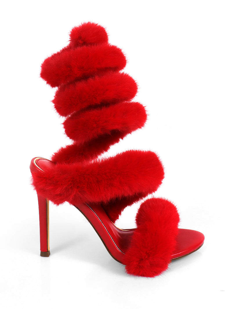 The Allure Fluffy Stiletto Sandal by Frederick's of Hollywood is a glamorous bright red heel with bold faux fur straps that wrap up the leg, showcased against a plain white background.