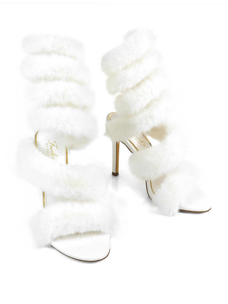 The Allure Fluffy Stiletto Sandal by Frederick's of Hollywood features glamorous white faux fur straps wrapping around the foot and ankle, making these sandals standout statement heels. Shown against a white background.
