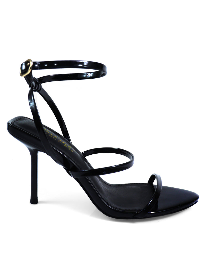 The Cynthia Pointy Toe Pencil Heel by Frederick’s of Hollywood is a black sandal with thin straps, a sleek glossy finish, and an ankle strap with a small buckle for an elegant, sophisticated look.