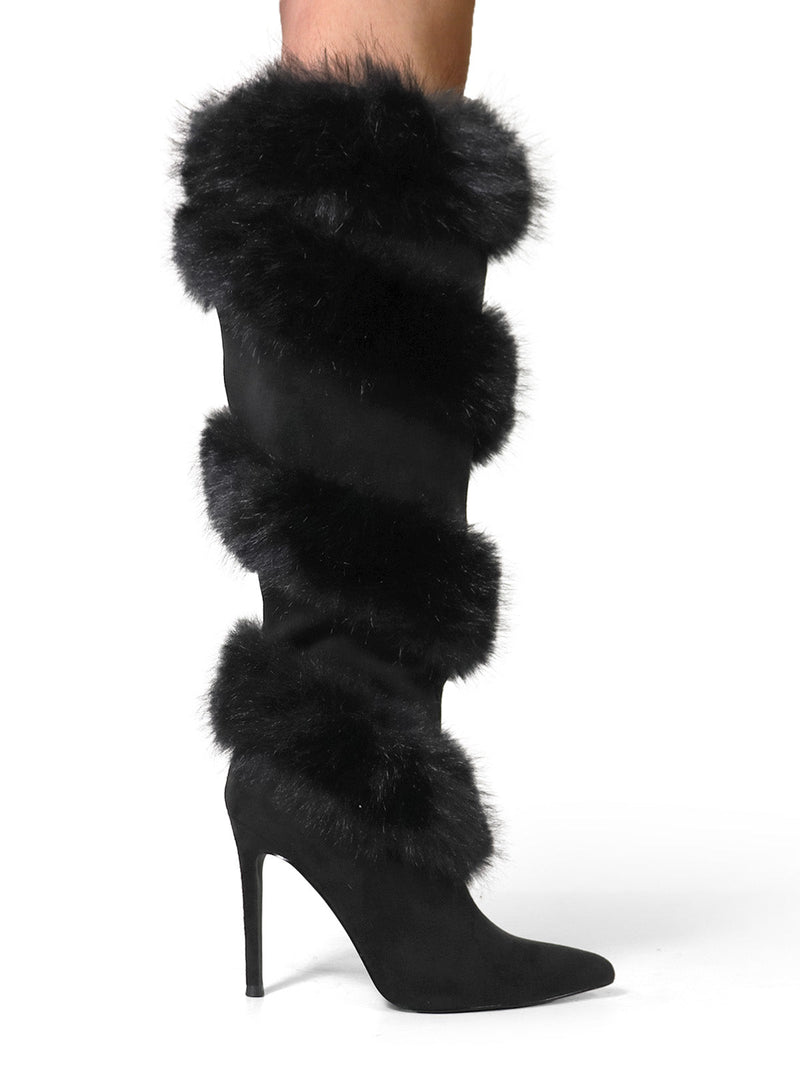 The Holly Feather Over the Knee High Boots by Frederick's of Hollywood are black suede, pointed-toe heels with three bands of black faux fur on the shaft, modeled with bare legs against a white background.