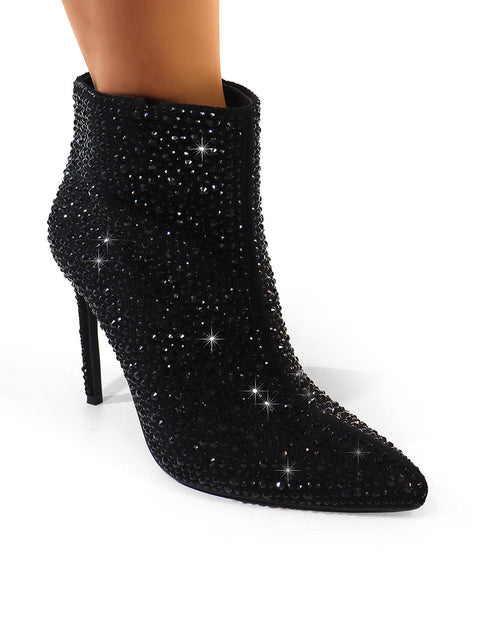 A close-up of Frederick's of Hollywood Izara Rhinestone Ankle Boots, featuring a pointed toe and stiletto heel, worn on a model’s foot against a white background.